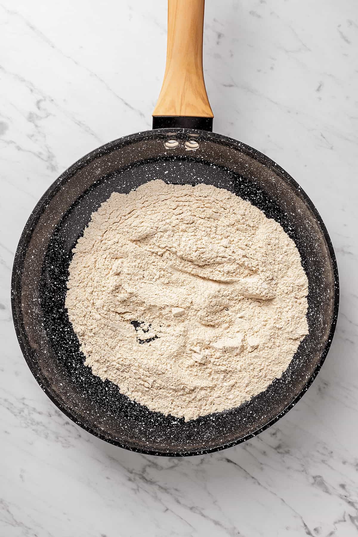 Overhead view of oat flour toasting in skillet