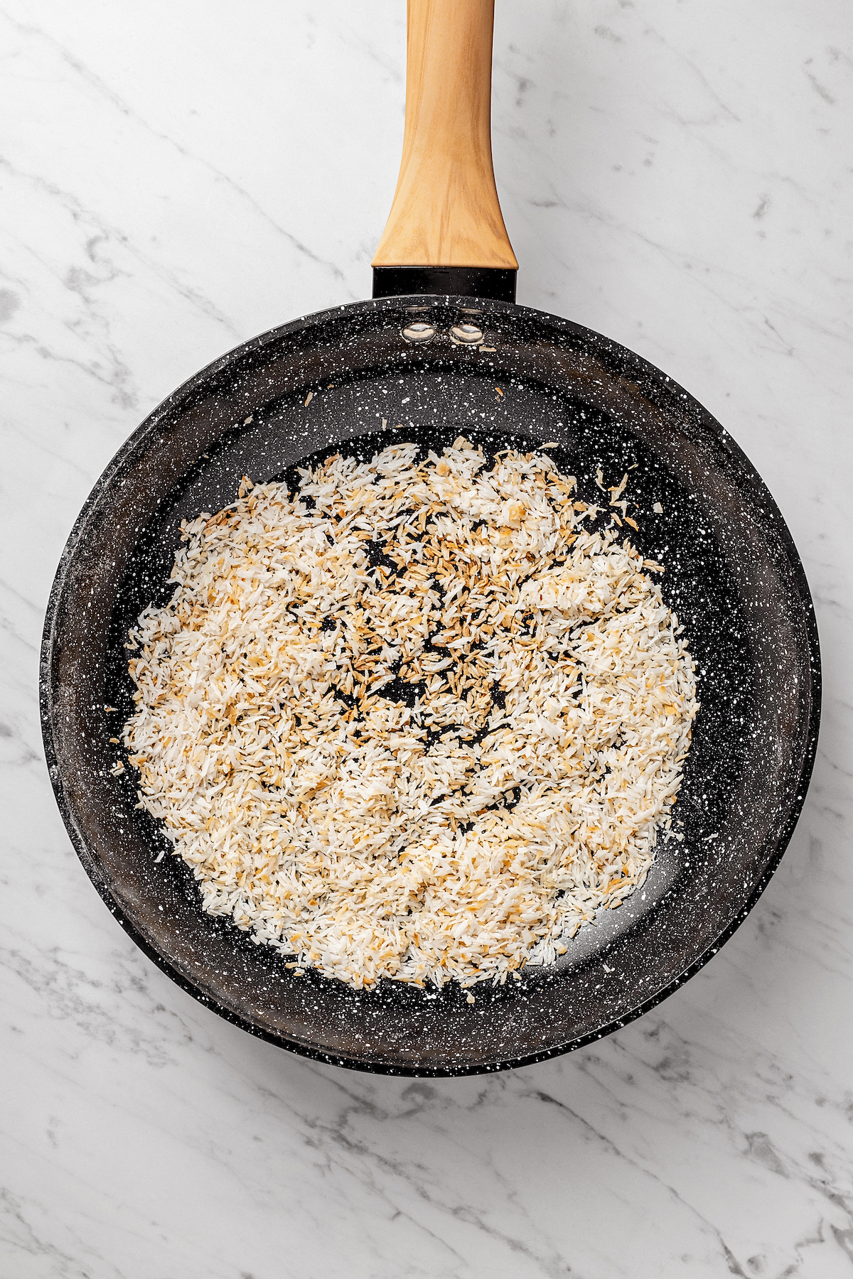 Overhead view of coconut toasting in skillet