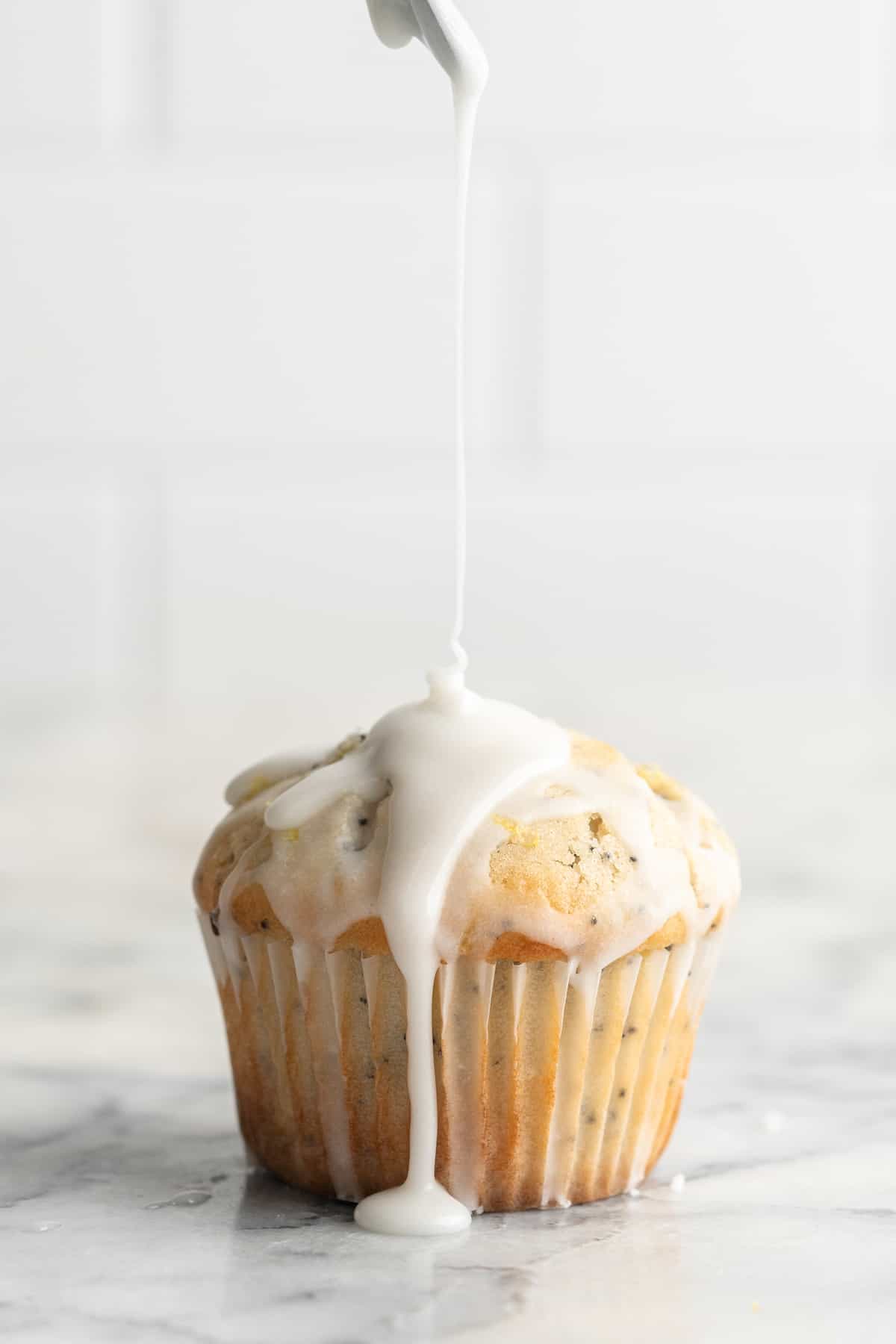 Drizzling glaze onto vegan lemon poppyseed muffin