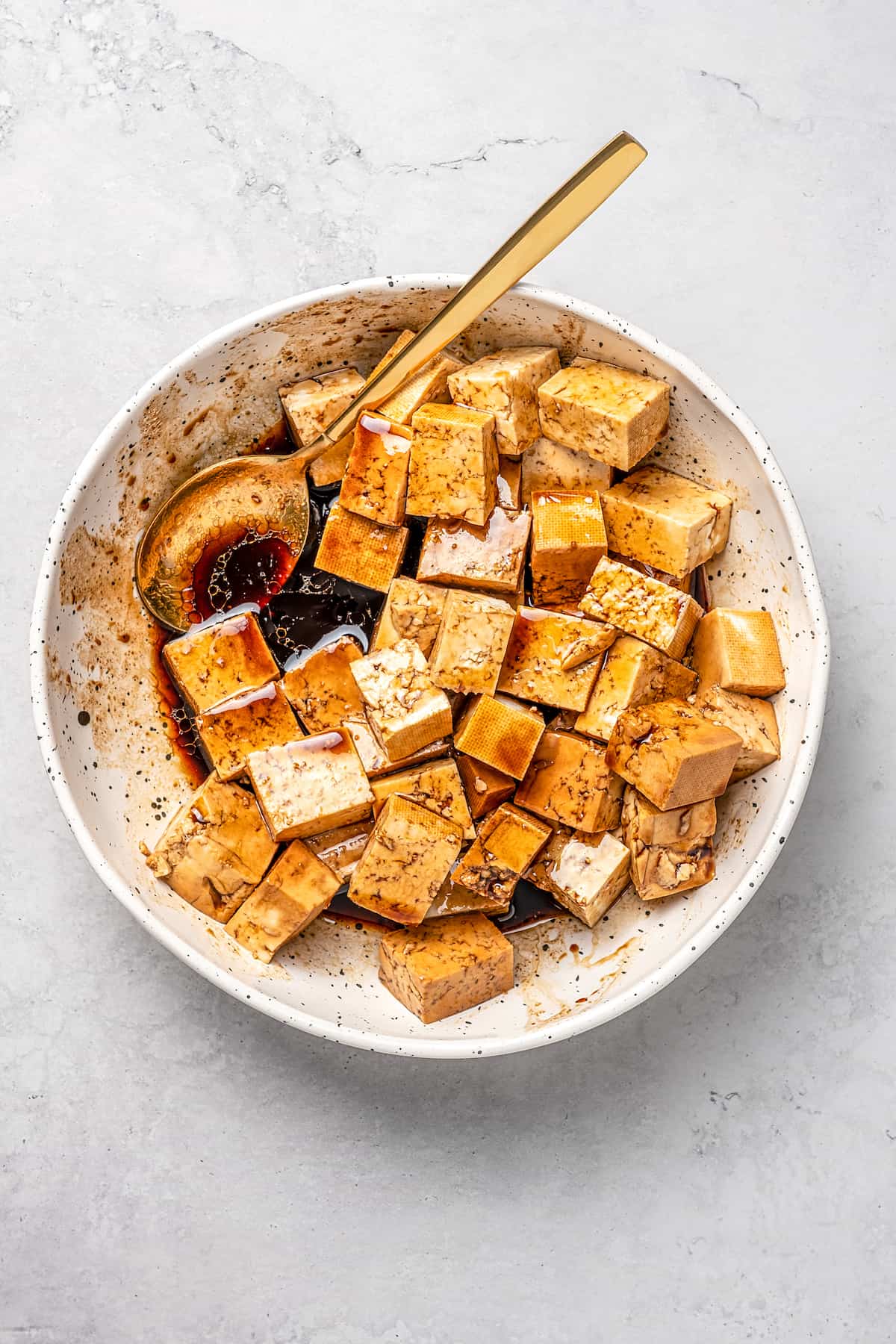 Overhead view of marinating tofu in dish with sauce