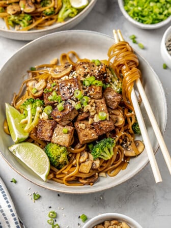 Bowl of vegan pad see ew with noodles wrapped around chopsticks