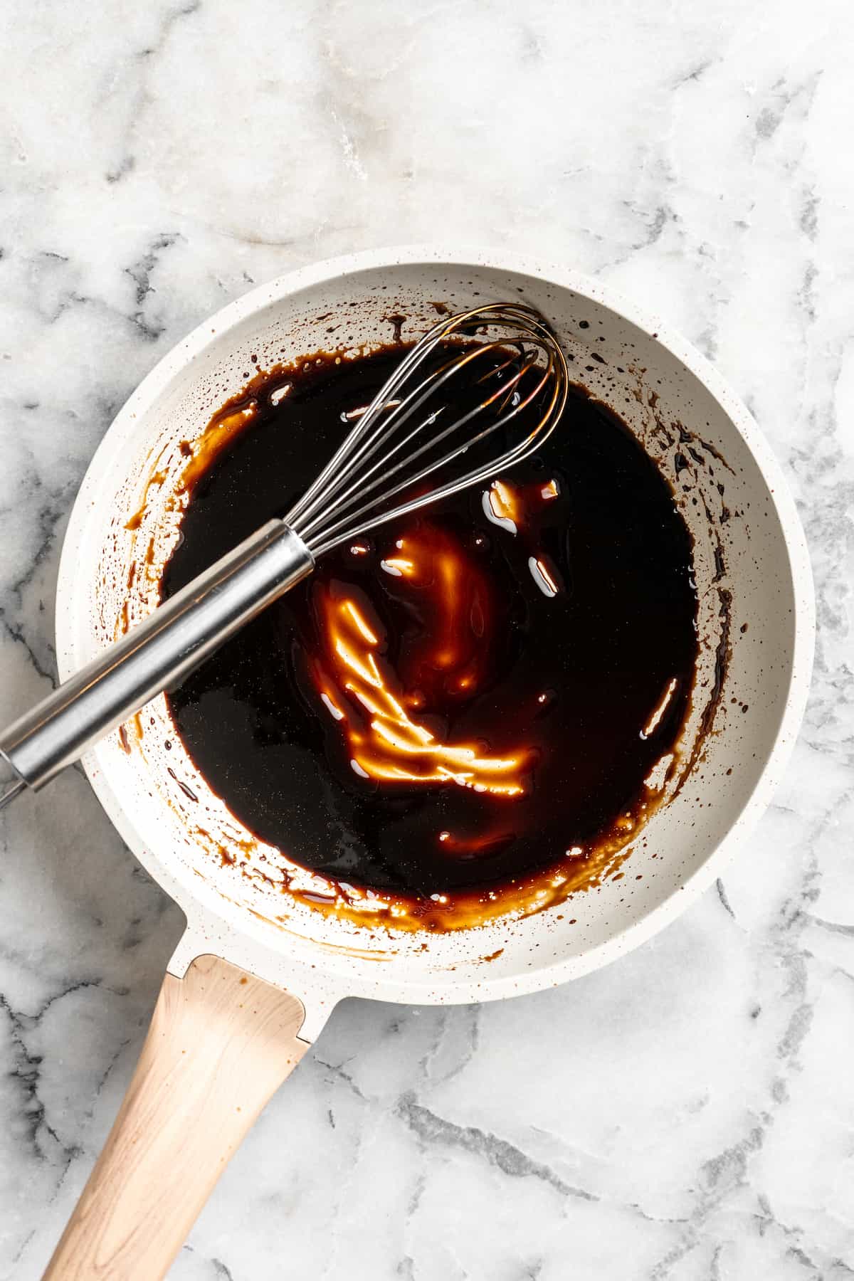 Overhead view of balsamic reduction in saucepan with whisk