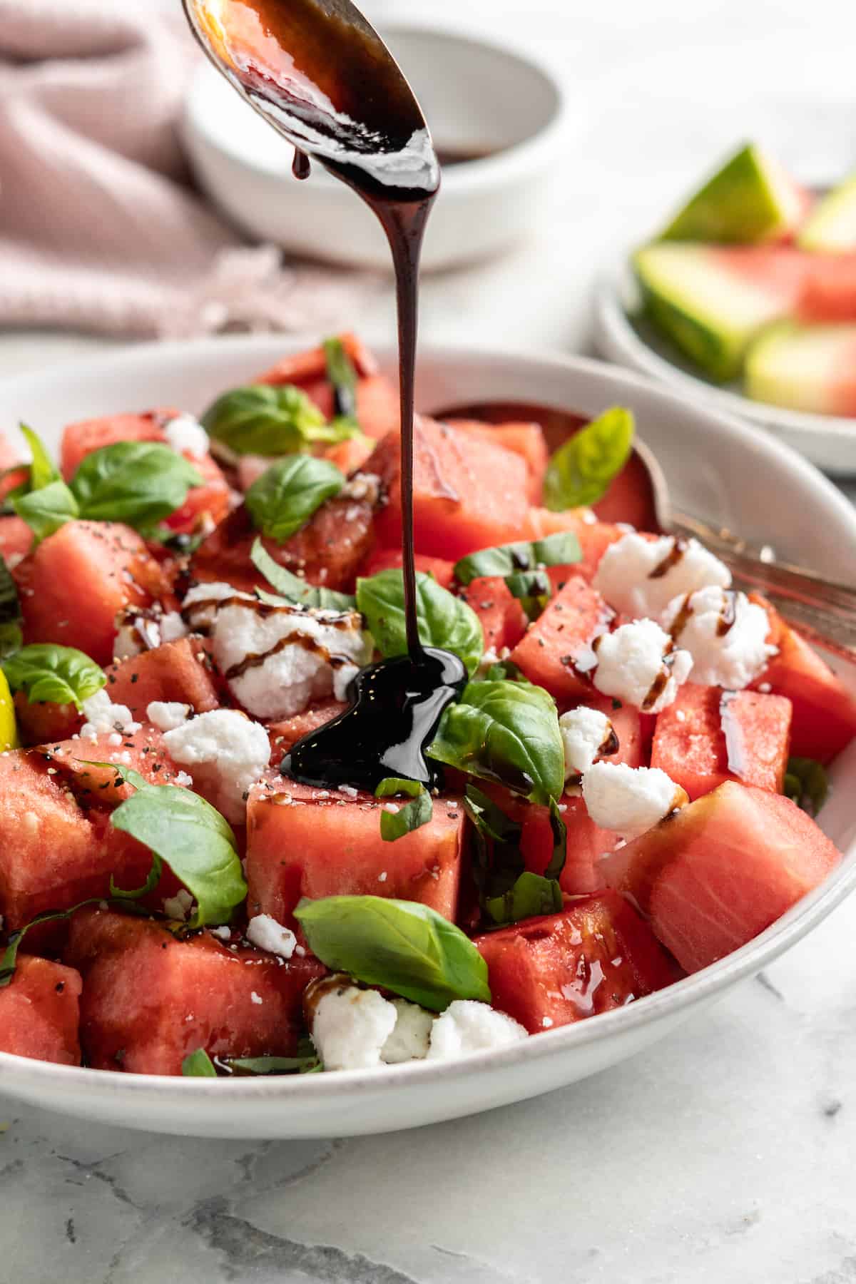 Pouring balsamic drizzle over vegan watermelon feta salad