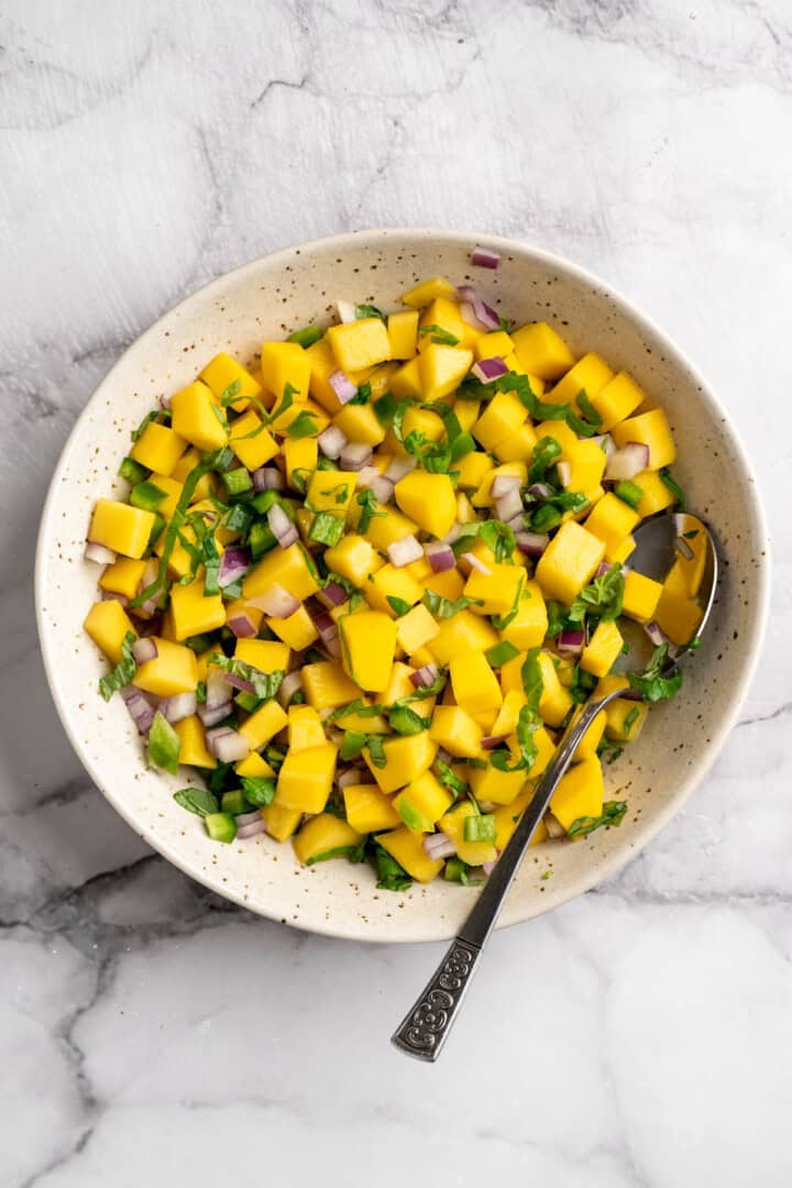 Mango basil salsa in bowl with spoon.