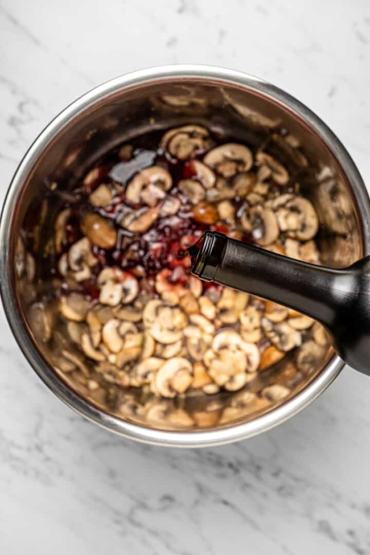 Pouring red wine into Instant Pot insert with risotto ingredients