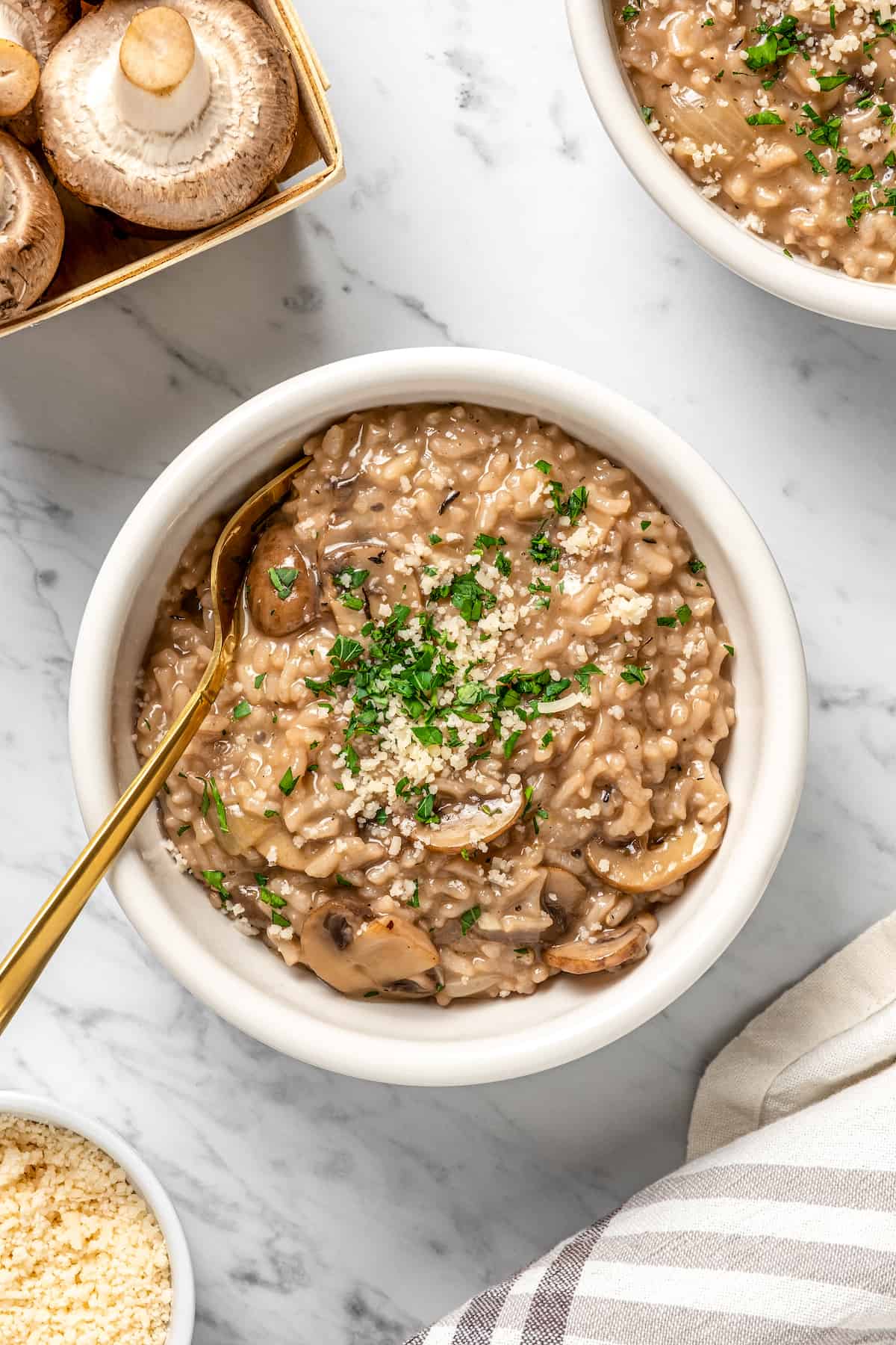 Overhead view of vegan Instant Pot risotto in white bowl with gold spoon