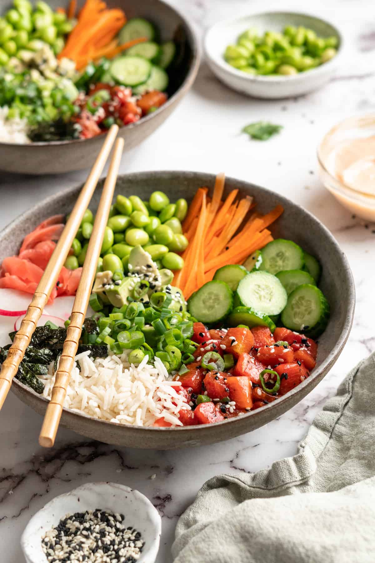 Vegan poke bowls with watermelon tuna, with toppings and garnishes in background