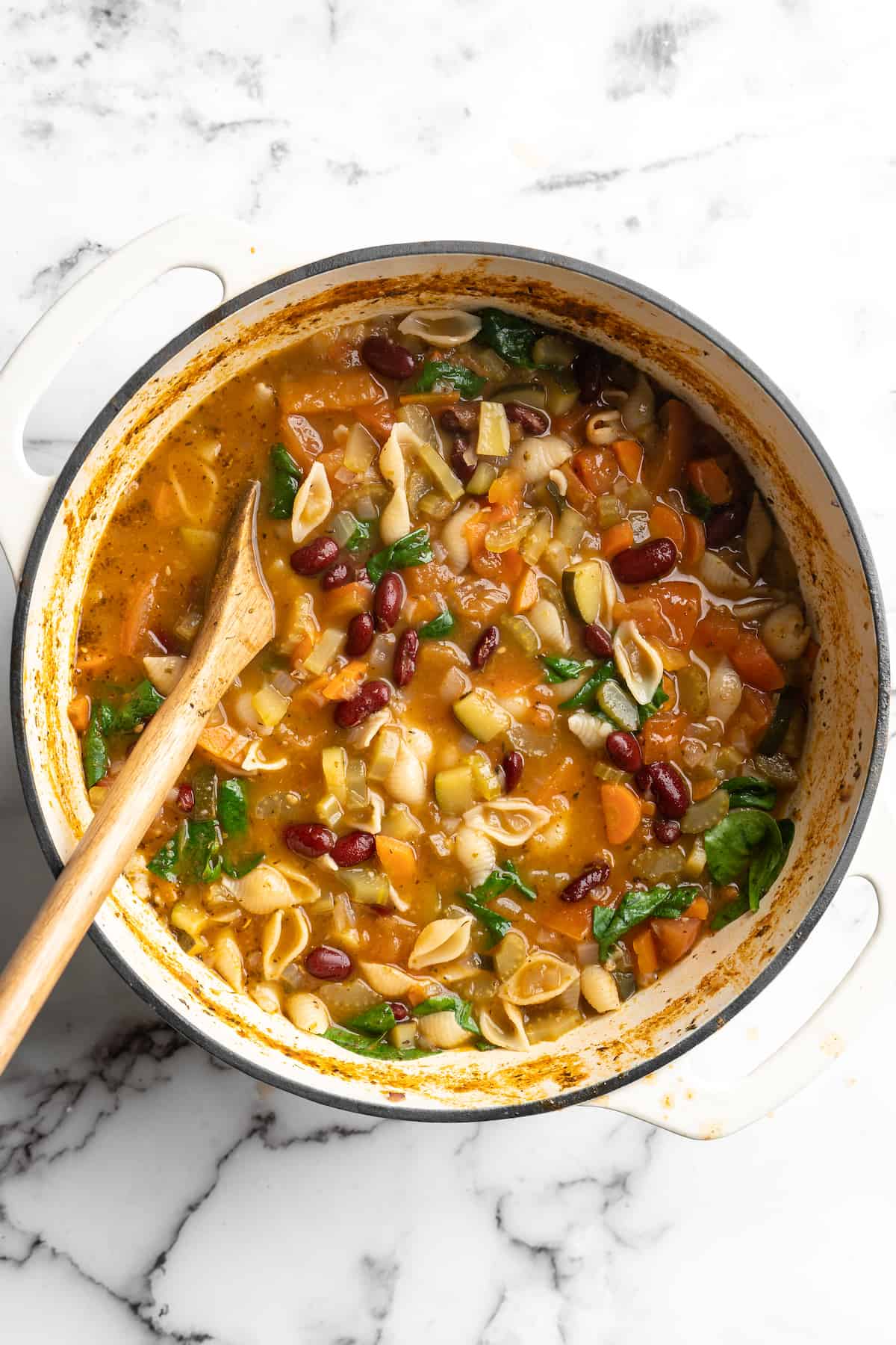 Overhead view of vegetable minestrone in pot with wooden spoon