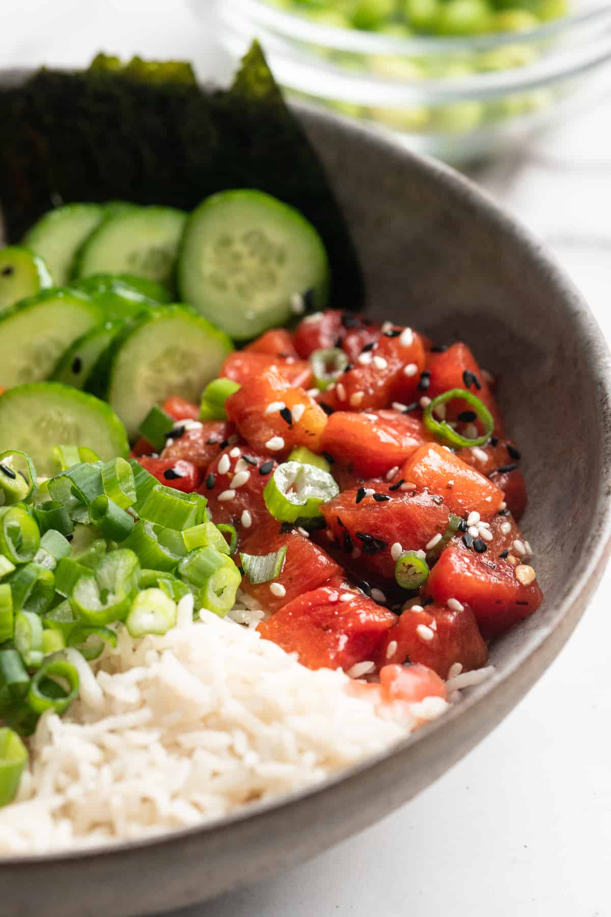 Watermelon tuna in vegan poke bowl with rice, cucumbers, and green onions