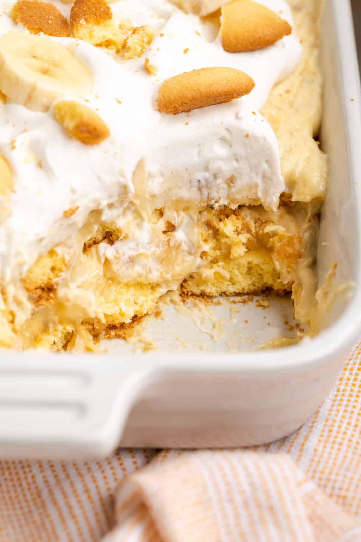 Vegan banana pudding in baking dish, with portion removed to show layers
