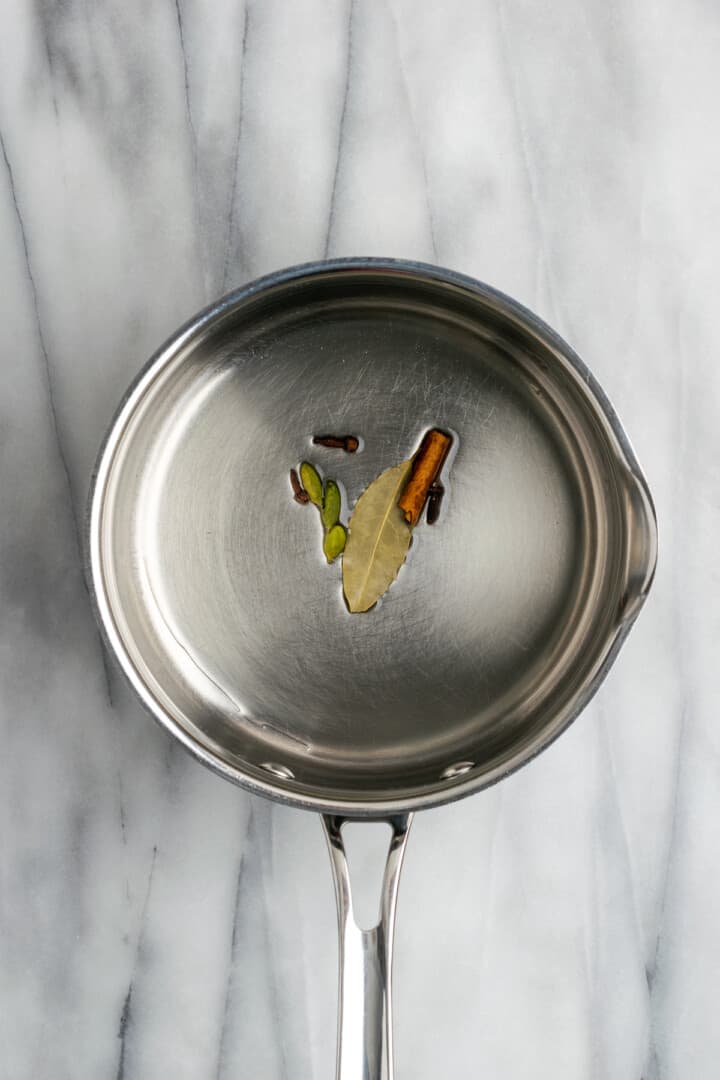 Whole spices and bay leaf cooking in oil in saucepan