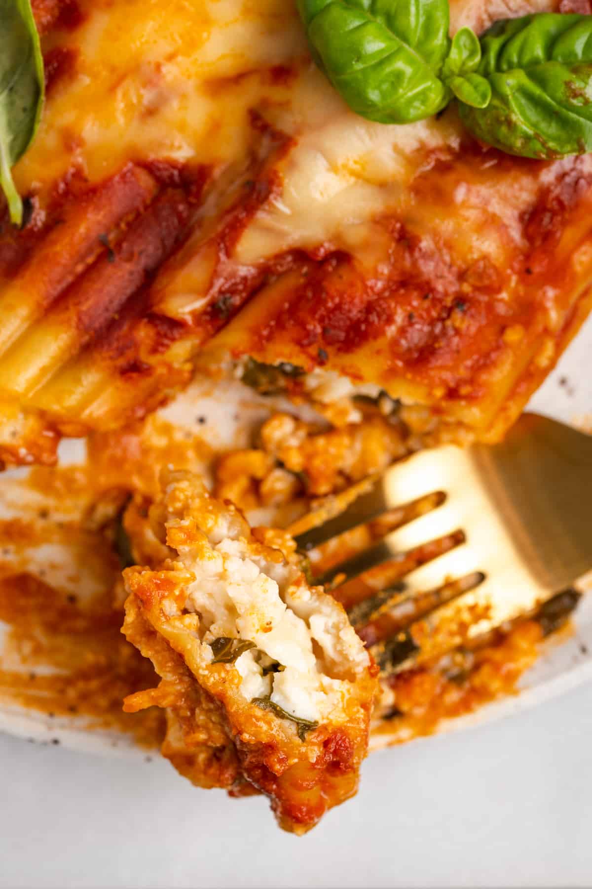 Forkful of vegan manicotti with spinach and ricotta filling