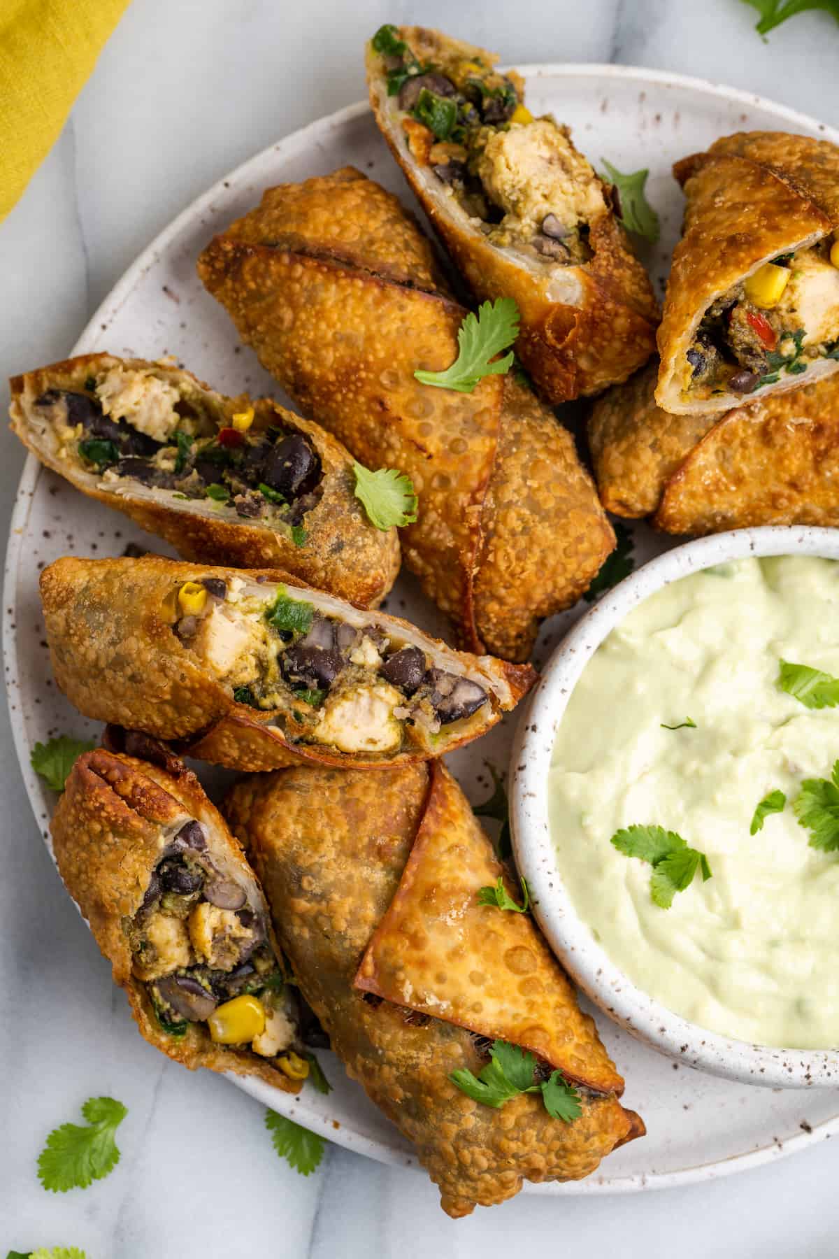 Overhead view of vegan southwest egg rolls on serving plate, with some cut open to show filling
