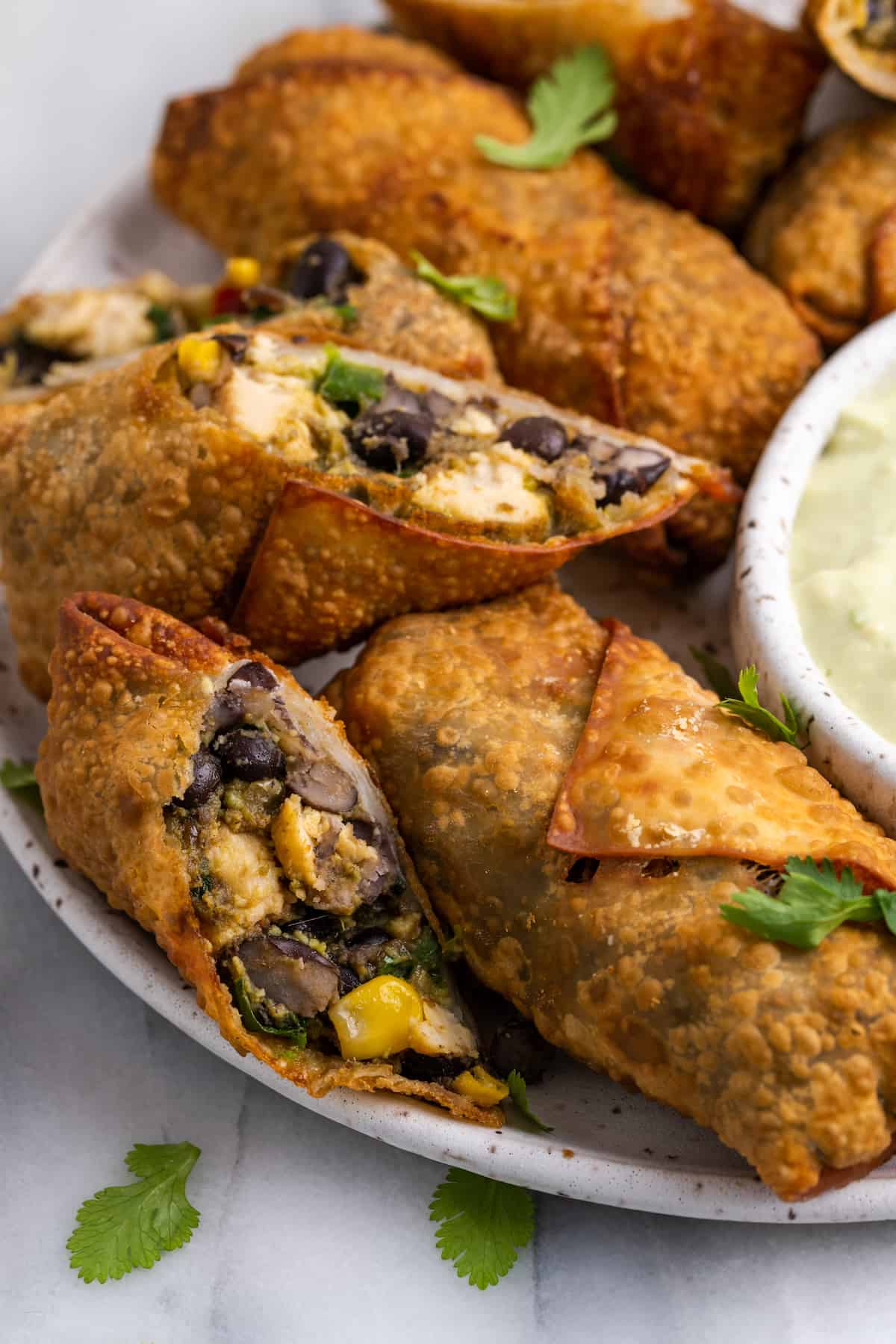 Vegan southwest egg rolls on serving platter with one cut open to show filling