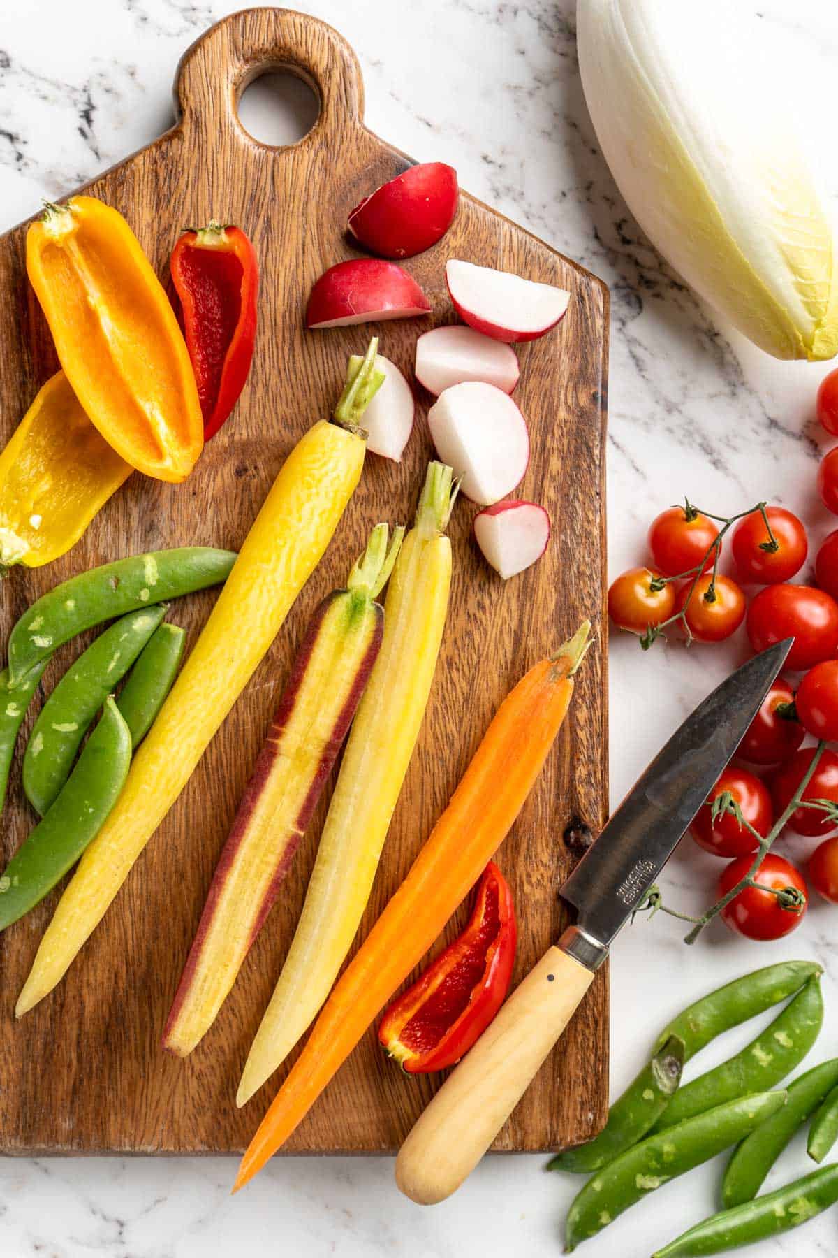 Overhead view of vegetables on wood cutting board with paring knife