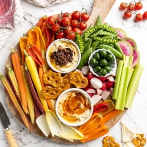 Overhead view of vegetable crudité platter with bowls of hummus and olives