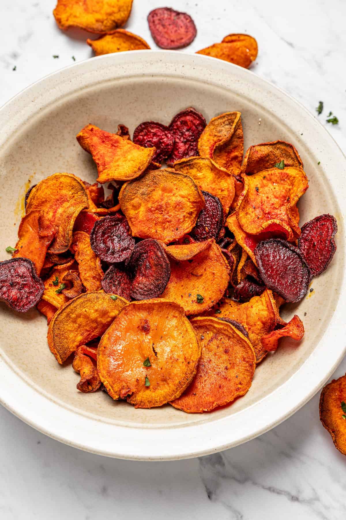 Overhead view of crispy air fryer veggie chips in shallow bowl