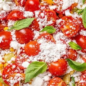 Closeup of vegan corn succotash with vegan feta, cherry tomatoes, and basil