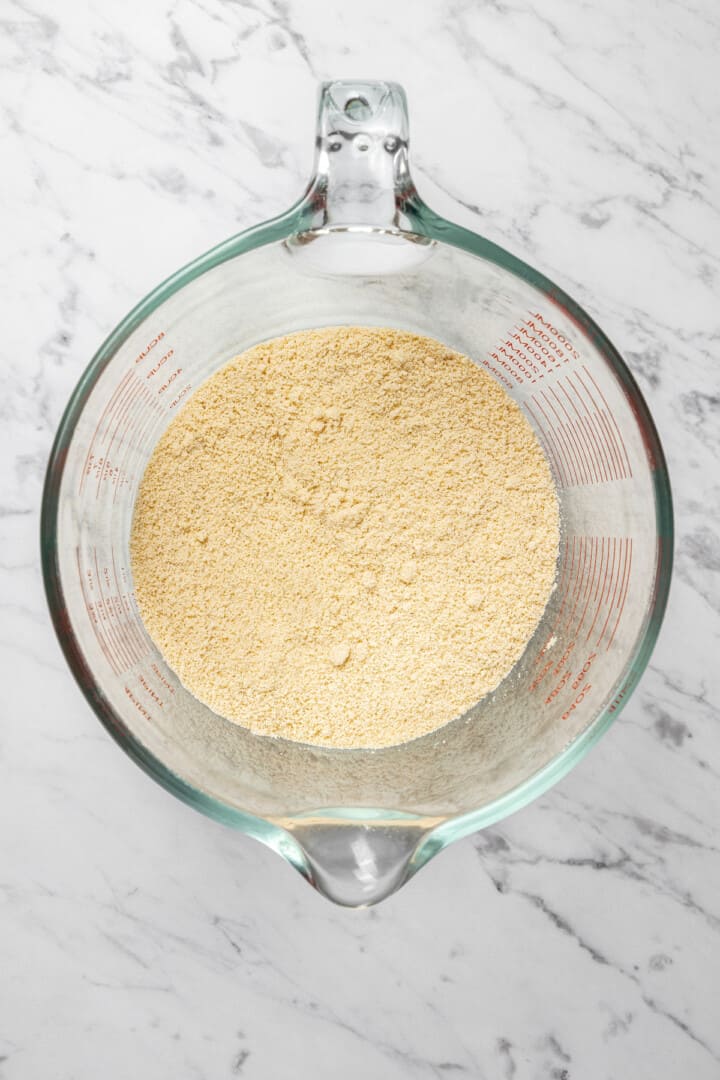 Overhead view of ground cashews in glass liquid measuring cup