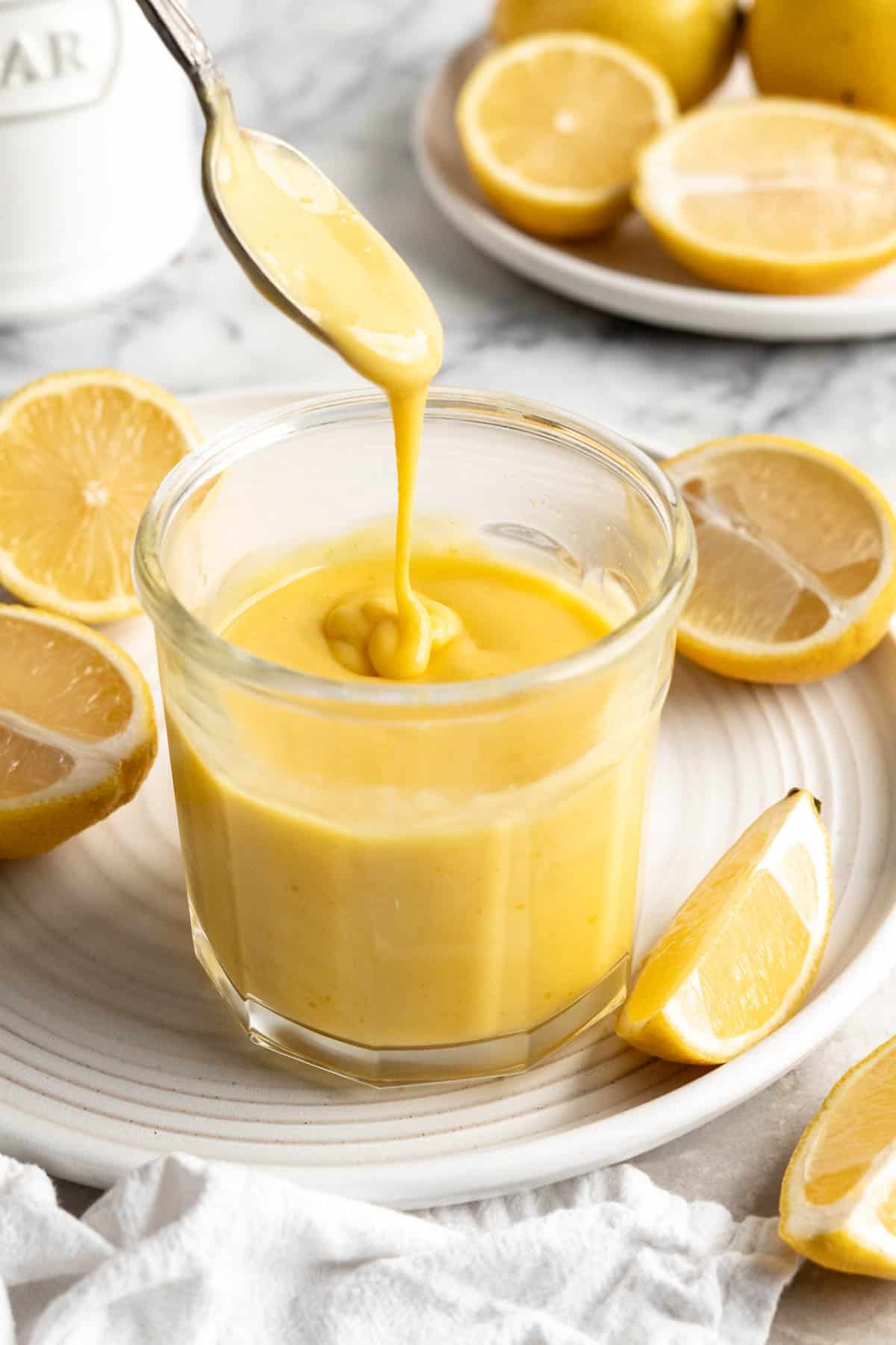 Spoon drizzling vegan lemon curd back into jar