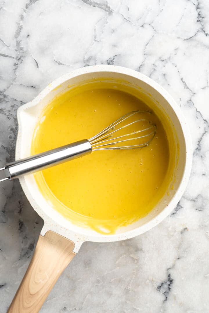 Overhead view of whisk in saucepan with lemon curd
