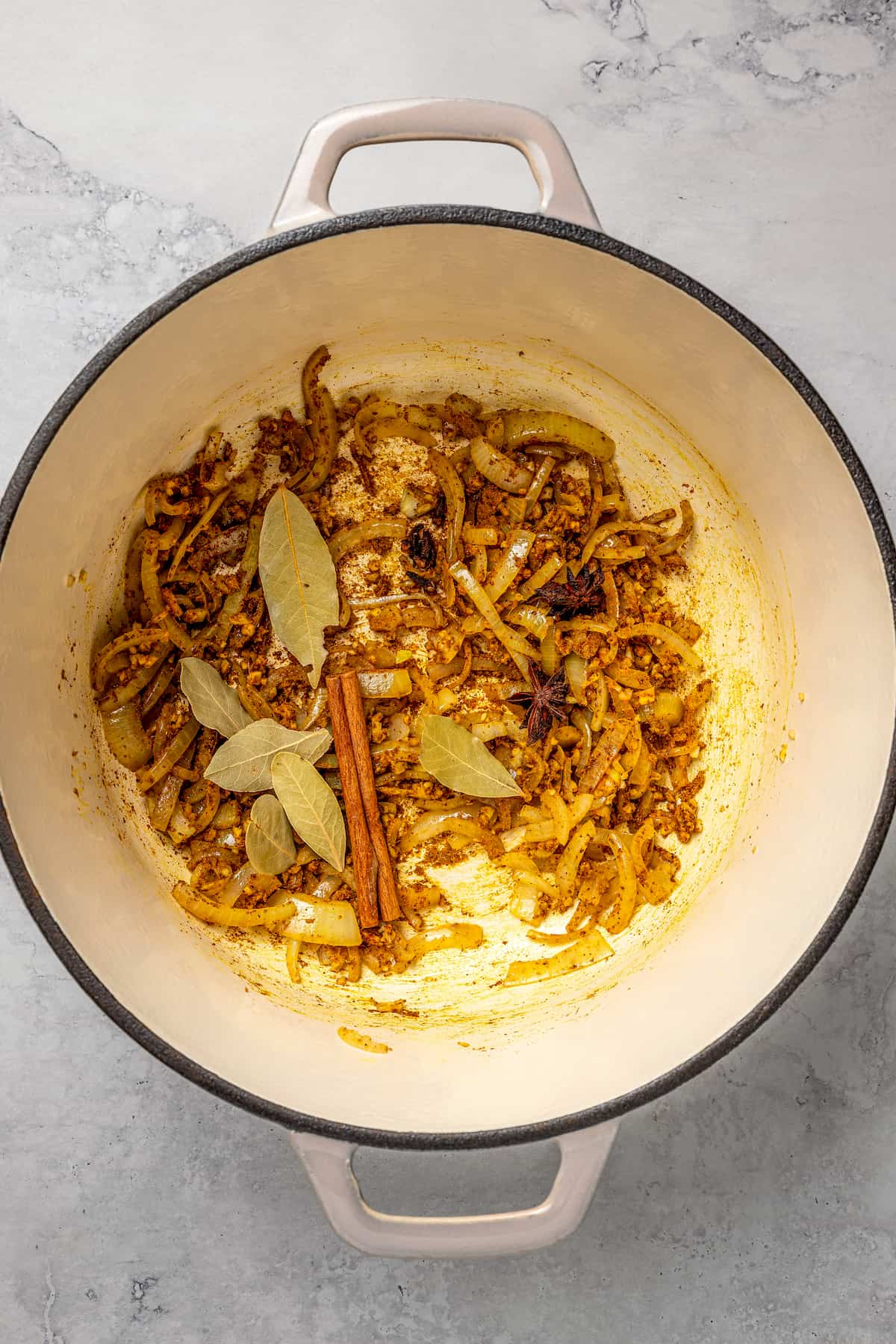 Overhead view of spices and onions in pot