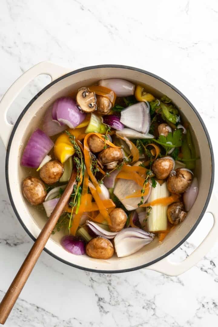 Overhead view of vegetable broth in pot with wooden spoon