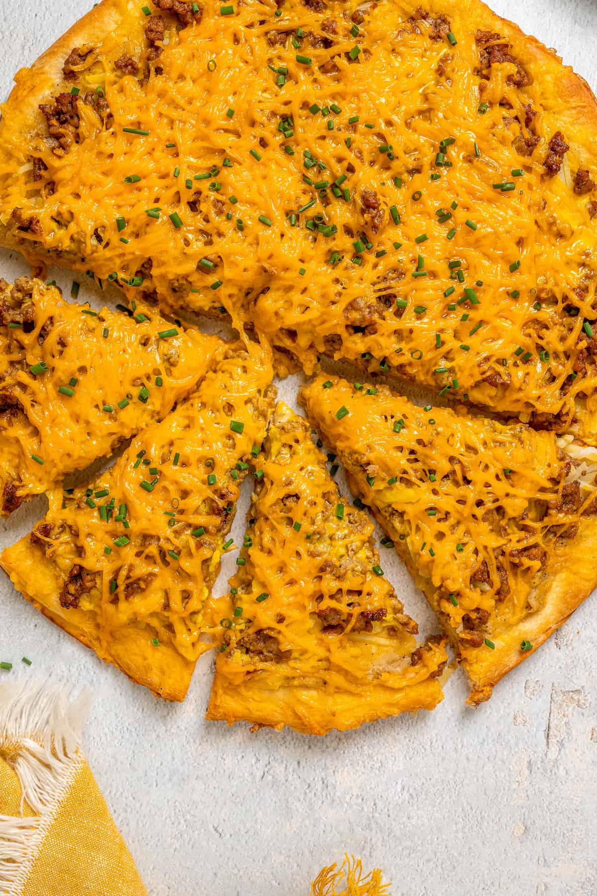 Overhead view of vegan breakfast pizza with four slices cut