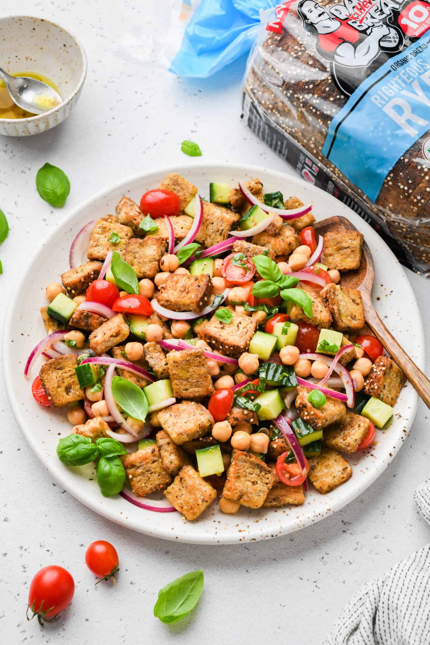 Overhead view of chickpea panzanella salad on platter with bread in the background