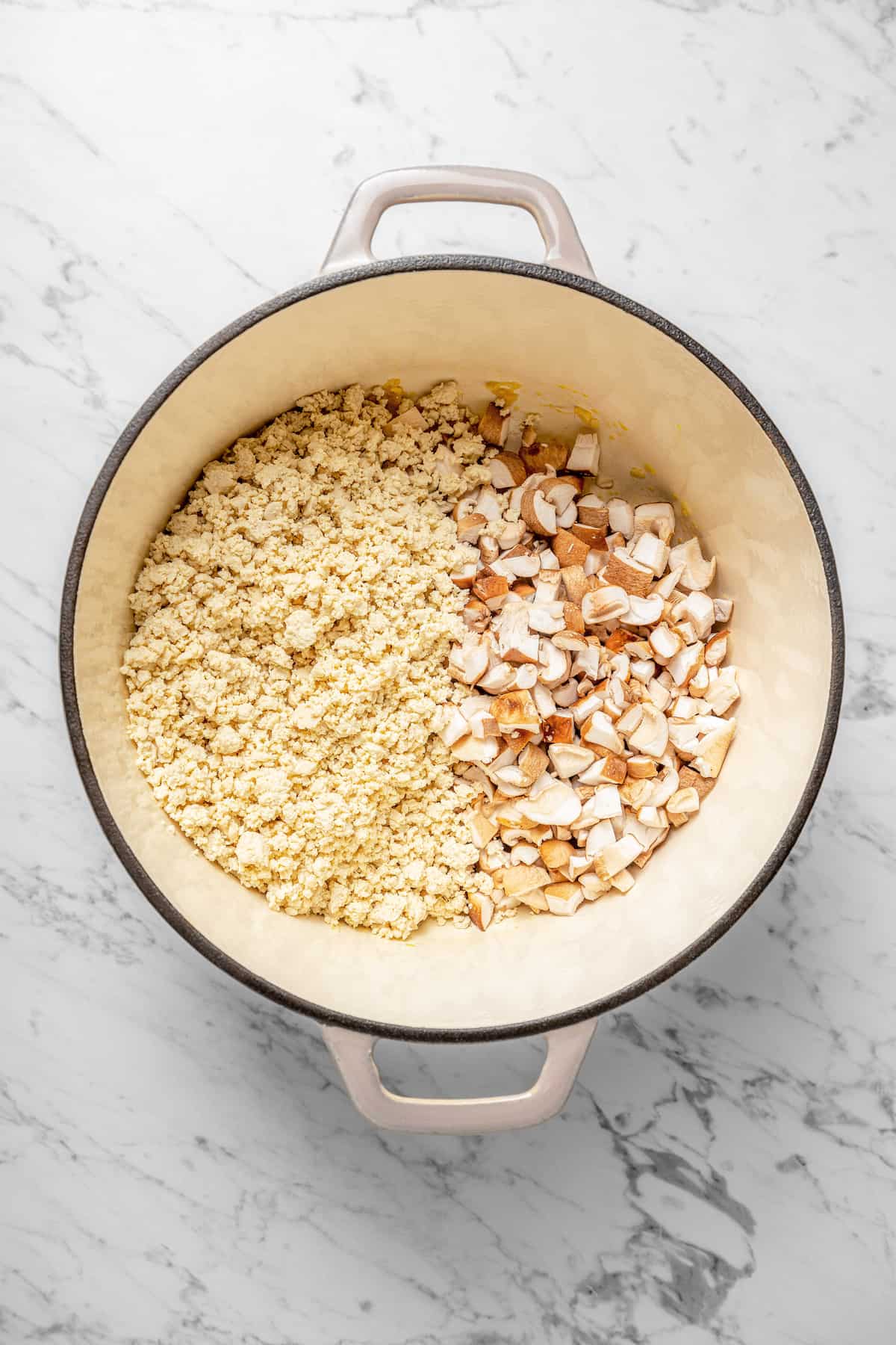 Overhead view of crumbled tofu and shiitakes in Dutch oven