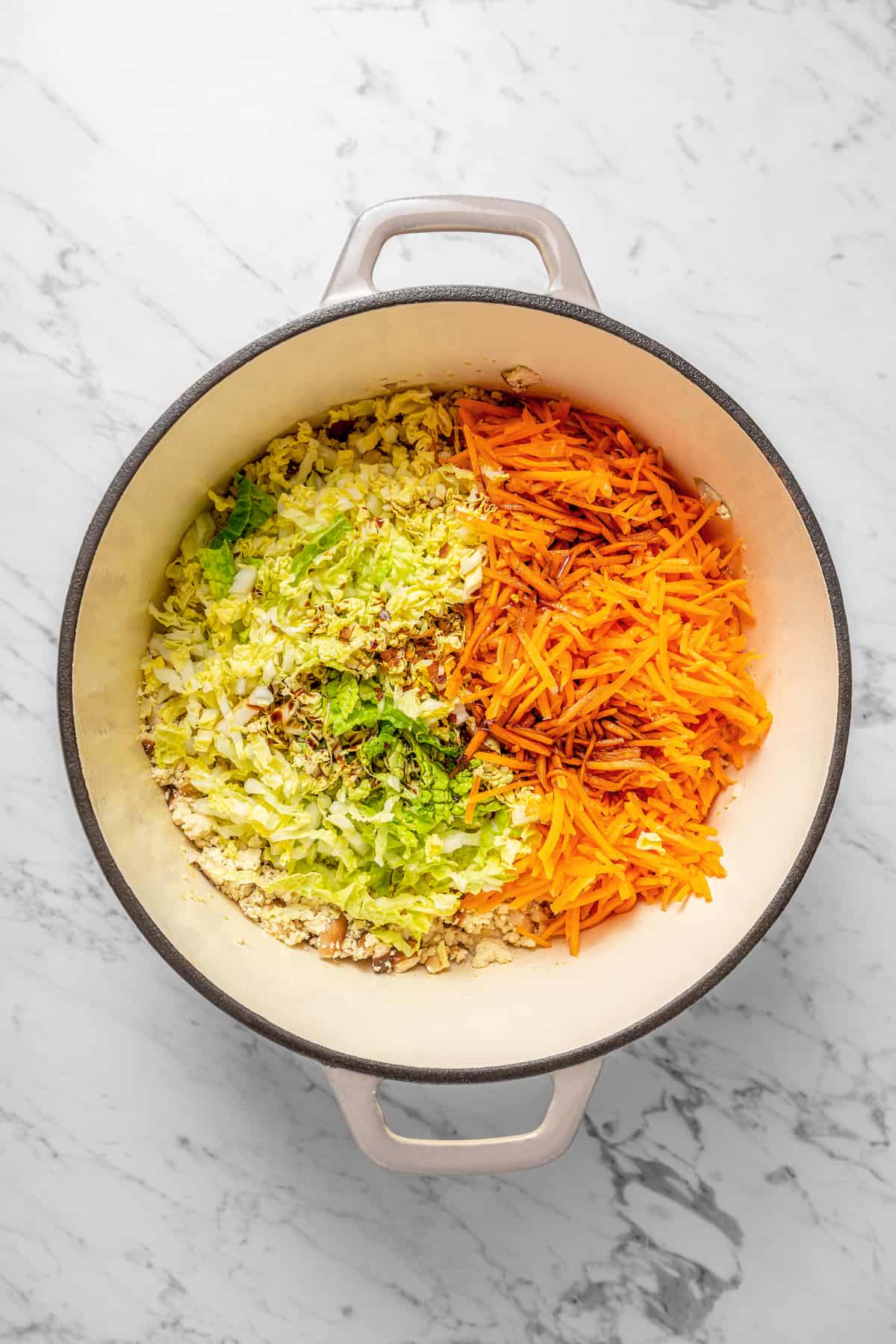 Overhead view of vegetables added to dumpling filling in Dutch oven