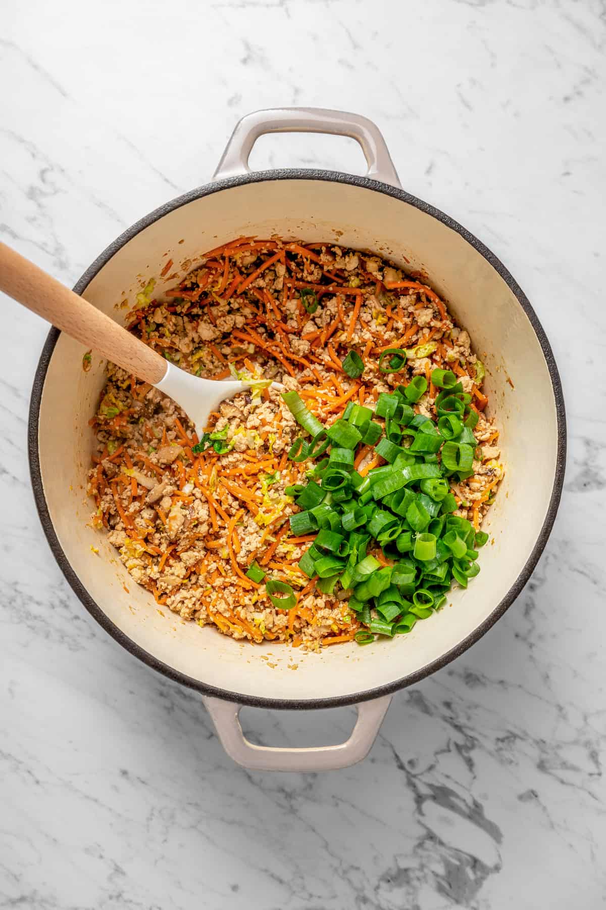 Overhead view of dumpling filling with green onions in Dutch oven