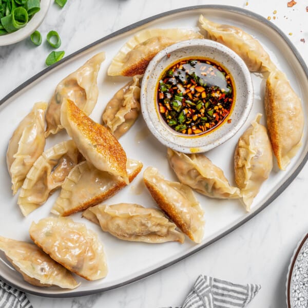 Overhead view of vegan dumplings on platter with bowl of dipping sauce