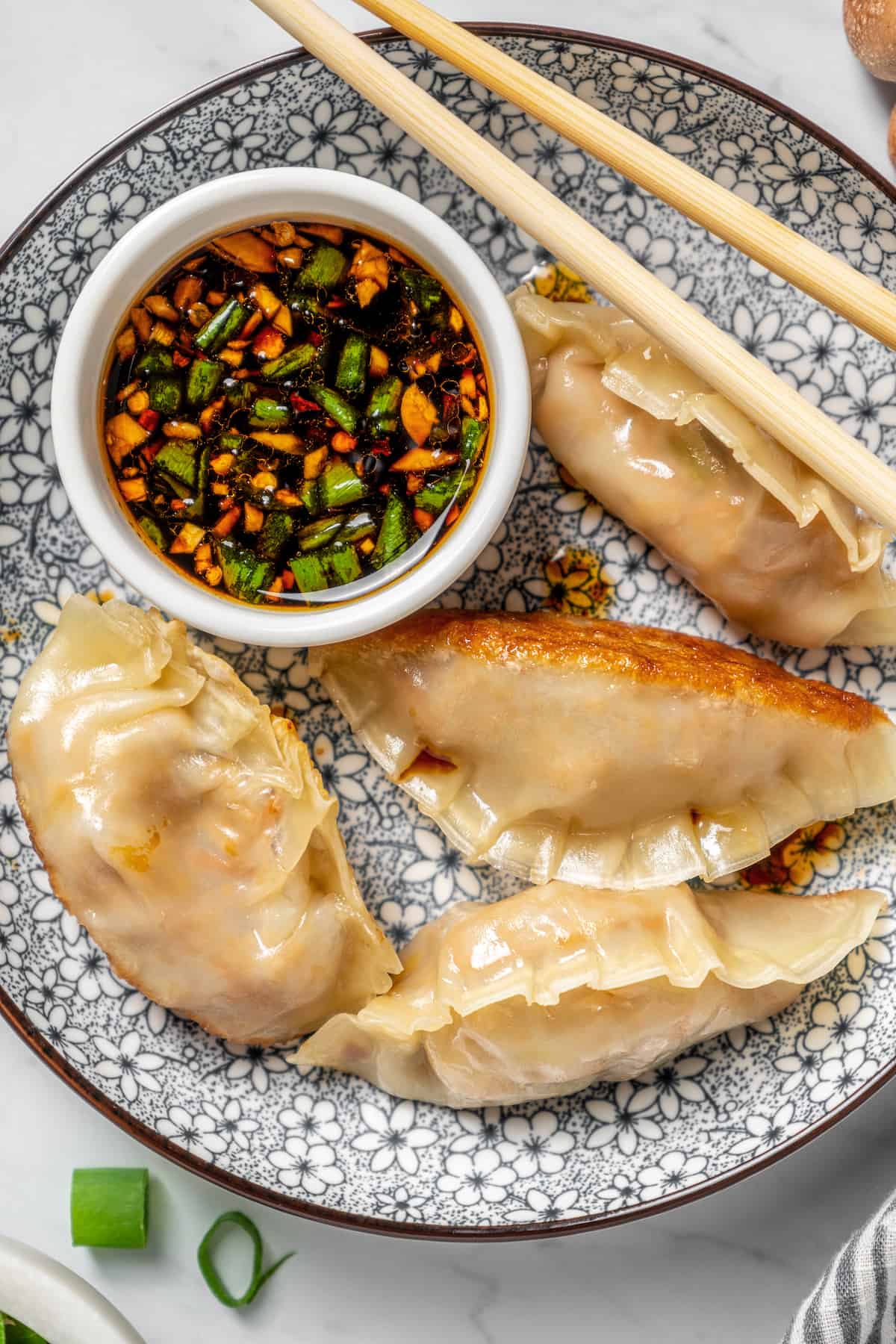Overhead view of vegan dumplings on plate with dipping sauce and chopsticks