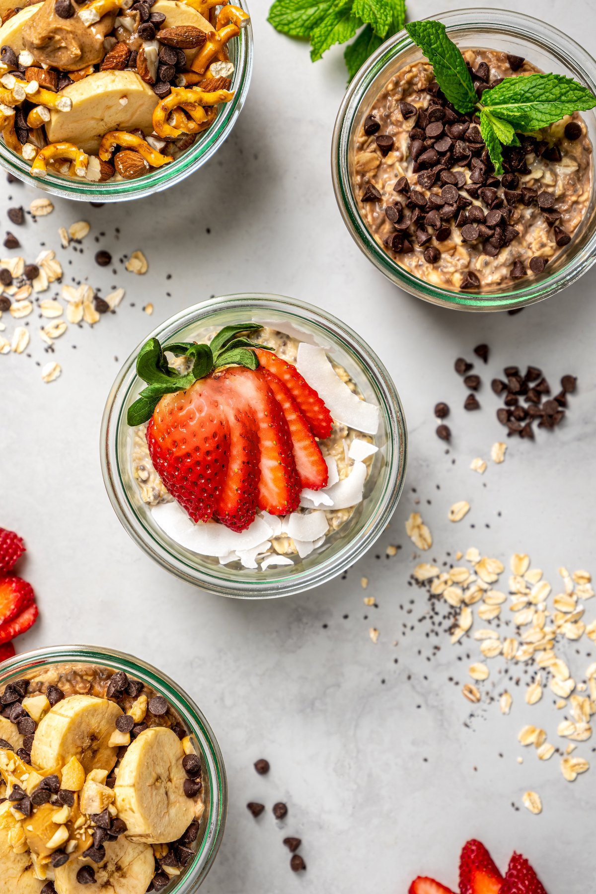 Jars of high-protein overnight oats with ingredients scattered on countertop