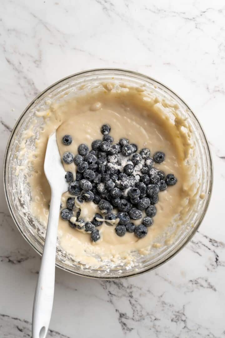 Overhead view of flour-dusted blueberries in bowl of batter