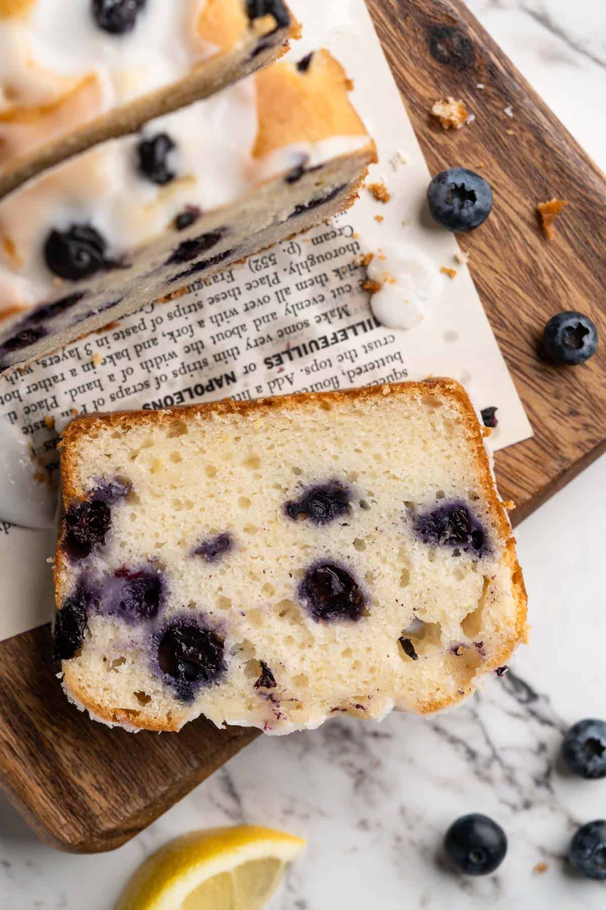 Overhead view of slice of moist vegan lemon blueberry bread on cutting board
