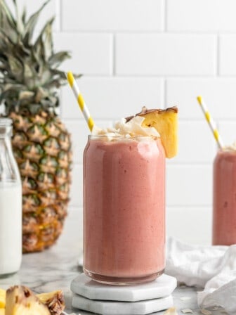 Strawberry pineapple smoothie in glass on two stacked coasters