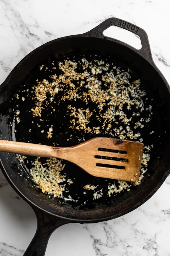 Overhead view of toasted garlic and oil in skillet
