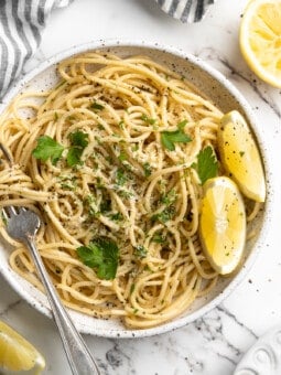 Overhead view of lemon pasta on plate with fork and lemon wedges
