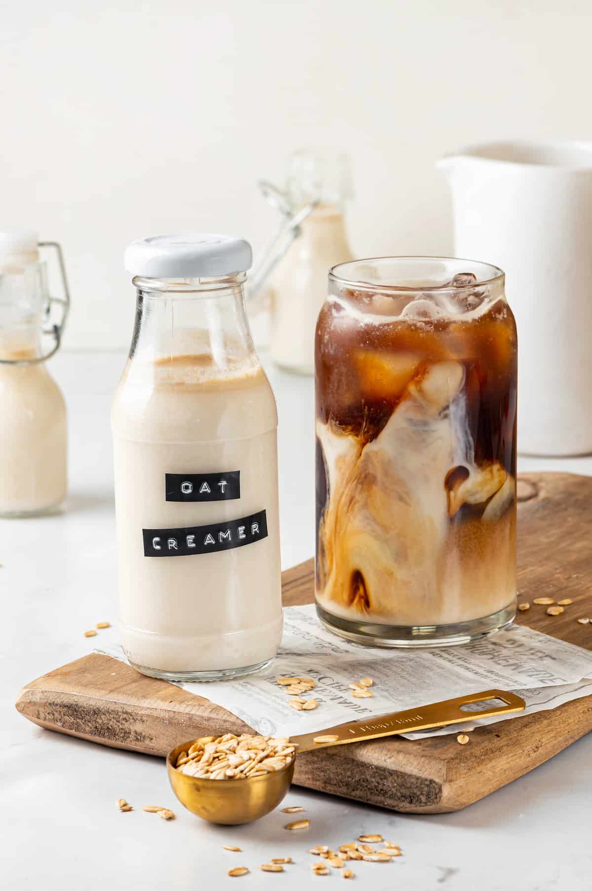 Oat milk coffee creamer set next to glass of iced coffee on cutting board