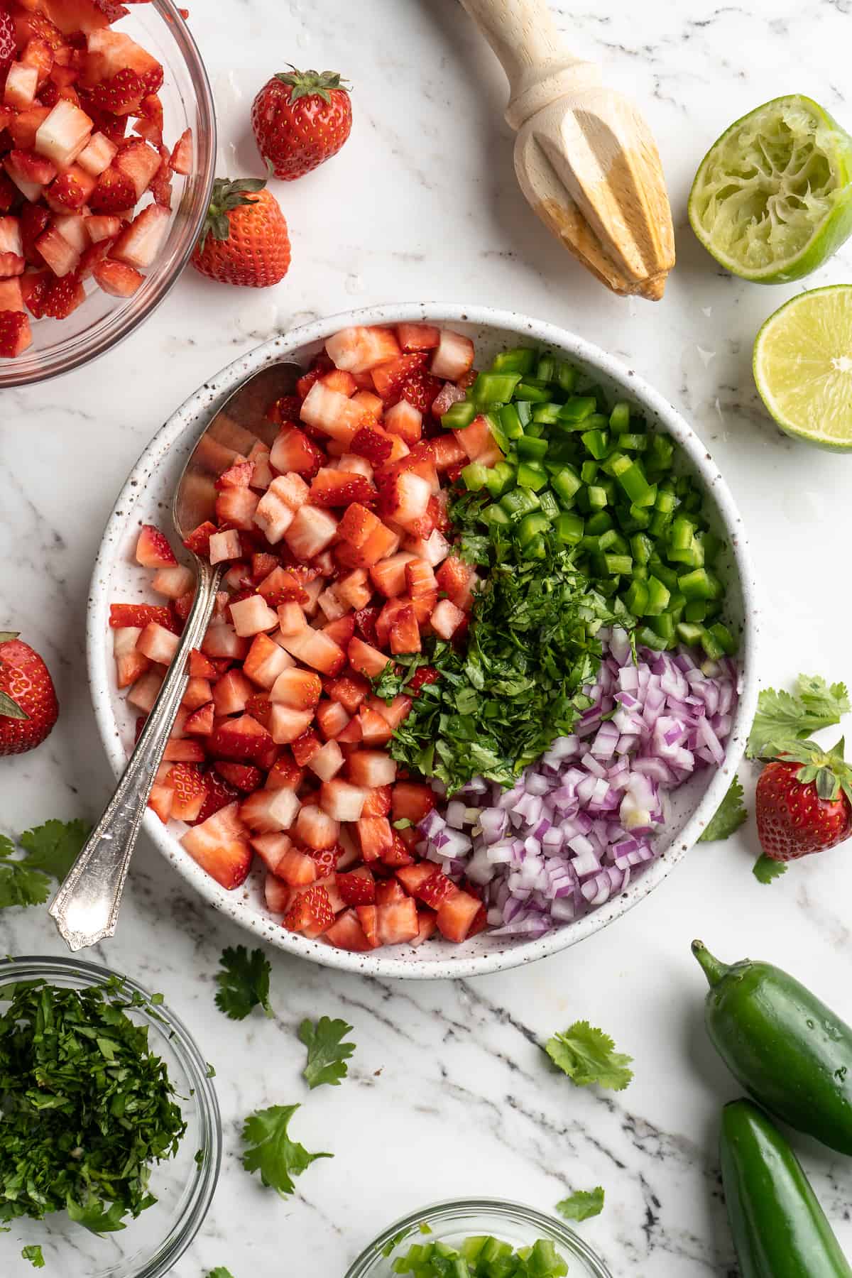 Overhead view of ingredients for strawberry salsa in bowl with spoon