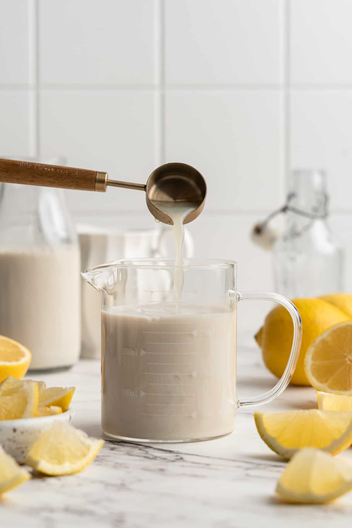 Pouring lemon juice into measuring cup of soy milk