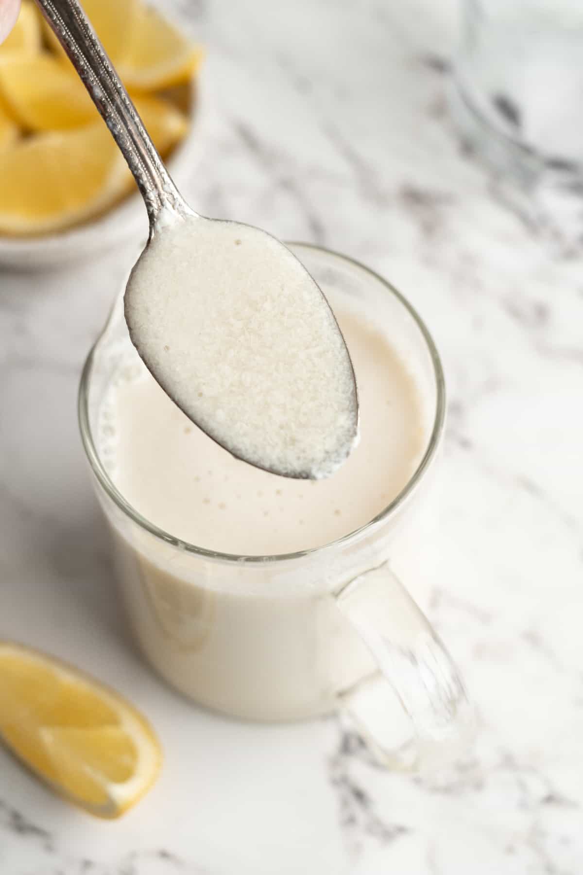 Spoonful of vegan buttermilk held over liquid measuring cup