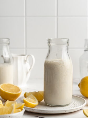 Jar of vegan buttermilk on plate with lemons