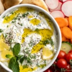 Overhead view of vegan tzatziki in bowl with drizzle of olive oil, fresh herbs, and lemon pieces - 7