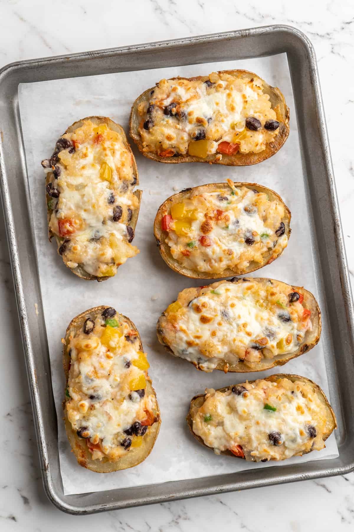 Overhead view of vegan loaded potato skins on parchment-lined baking sheet