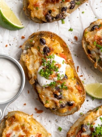 Overhead view of healthy loaded potato skin topped with chives, vegan bacon, and sour cream
