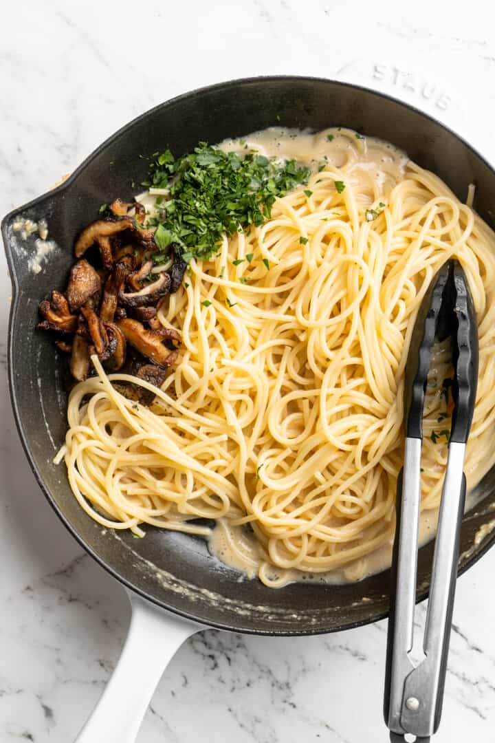 Overhead view of miso butter pasta in skillet after adding mushrooms and parsley