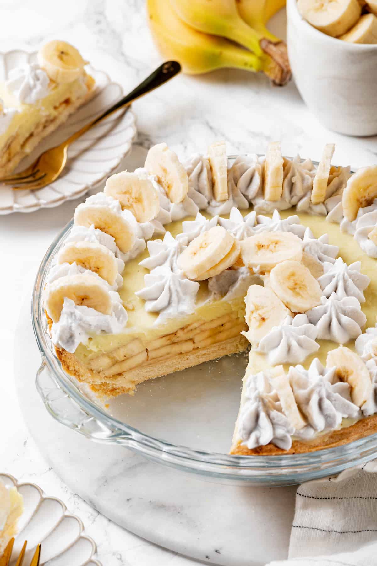 Banana cream pie in glass pie plate with two slices removed